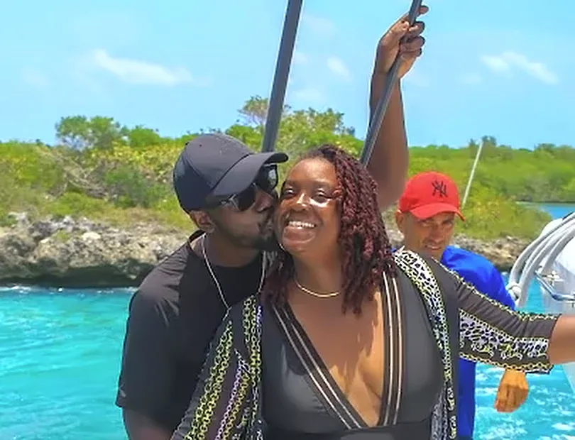 A man kisses a smiling woman on a boat ride with bright blue water.